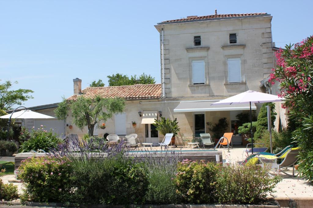 FronsacLes charmes de Vincent - le loft Cabernet的房屋设有带椅子和遮阳伞的庭院
