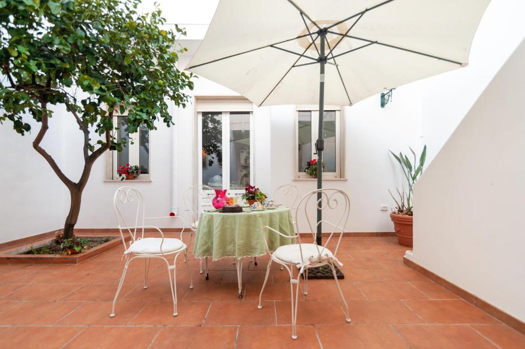SquinzanoLa dimora del Cavaliere di Squinzano的庭院配有桌椅和遮阳伞。