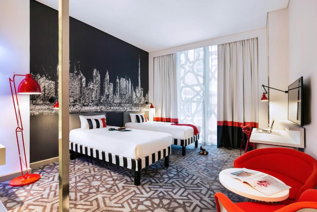 迪拜宜必思尚品迪拜机场酒店的酒店客房,设有两张床和一张红色椅子