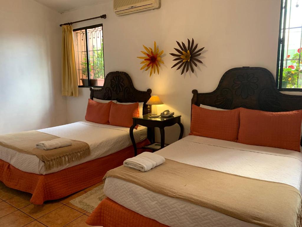圣萨尔瓦多拉珀萨达德尔安吉酒店的一间卧室配有两张带橙色枕头的床