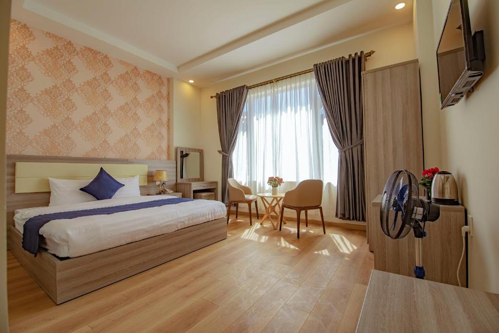 大叻Khanh Uyen 1 Hotel的酒店客房,配有一张床和一张桌子及椅子