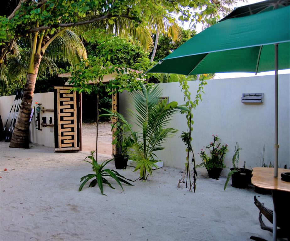 Omadhoo库里海滩景观旅馆的一个带桌子和遮阳伞的庭院