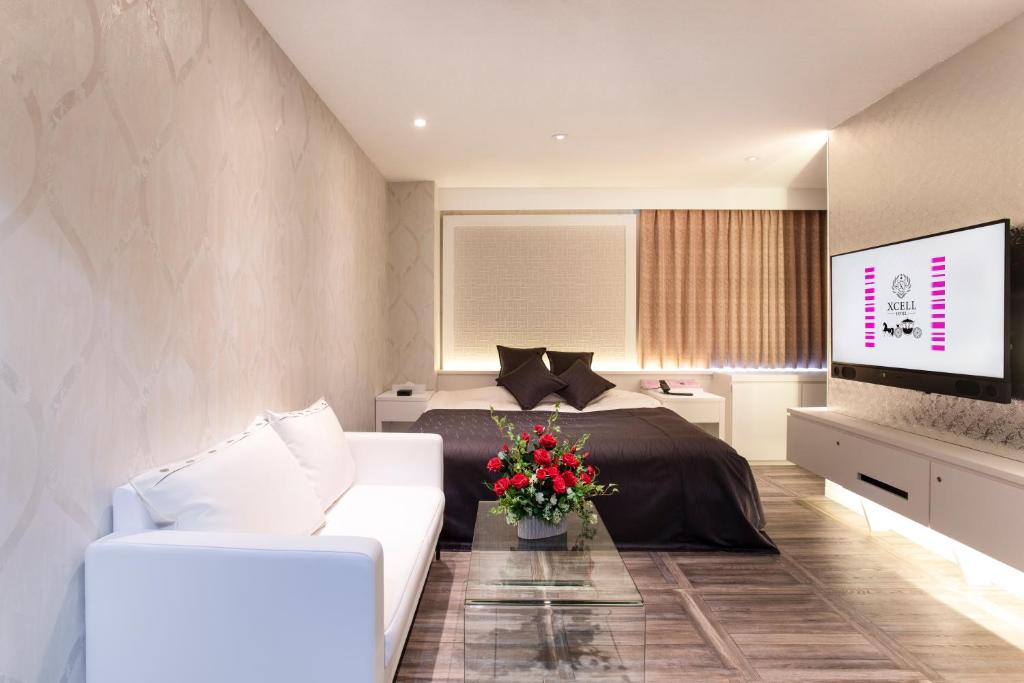 福山HOTEL xcell的一间卧室配有一张床、一张沙发和一台电视。
