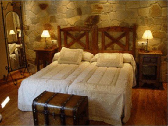 San Martín de Castañeda乡村休闲旅游中心酒店的卧室配有一张带行李箱的大型白色床