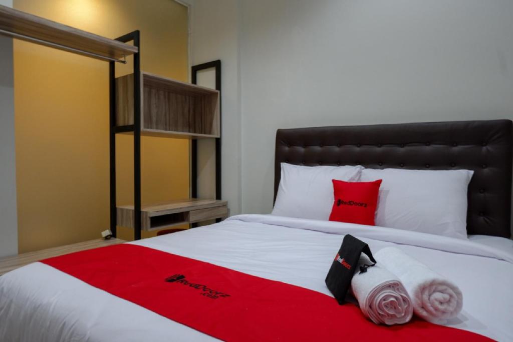 三宝垄RedDoorz @ Jalan Kartini Semarang的一张铺有红白床单和红色枕头的床