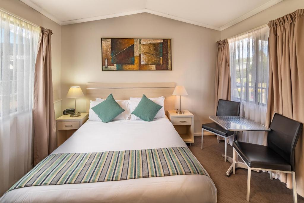 Emu Plains比格斯尼皮恩河假日公园的一间卧室配有一张床、一张桌子和一把椅子