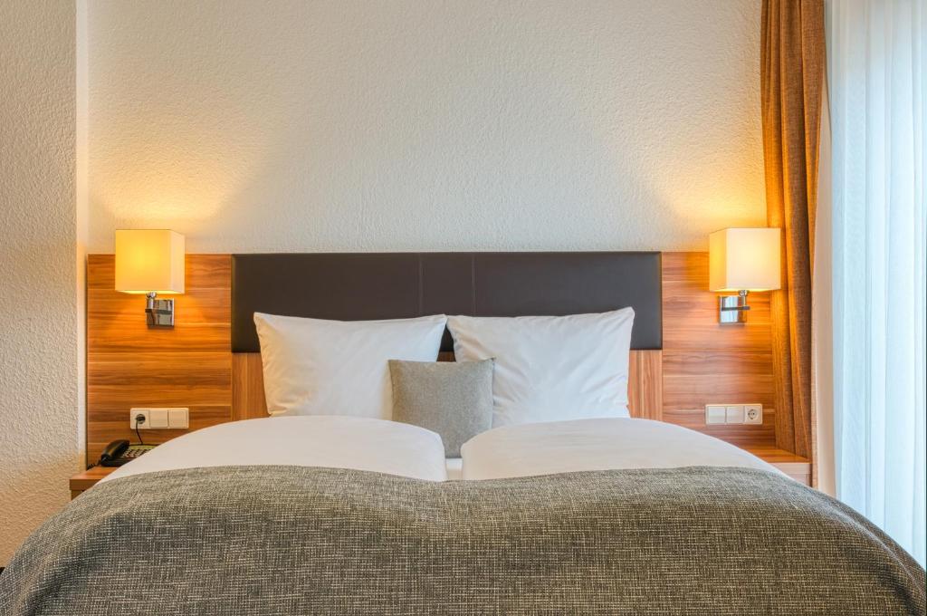 斯图加特Centro Hotel Sautter的一间卧室配有一张大床和两盏灯