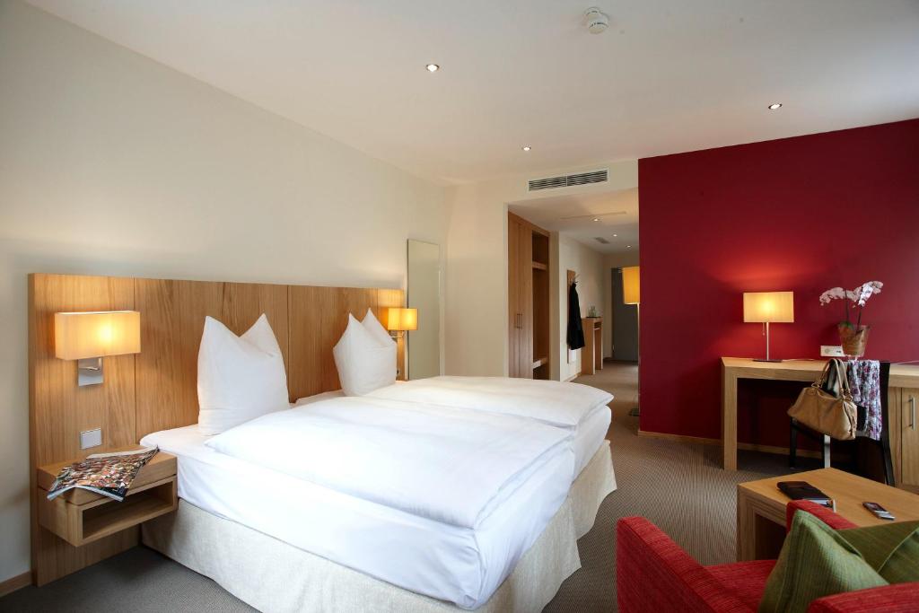 梅明根福肯酒店的红色墙壁的房间里一张大白色的床