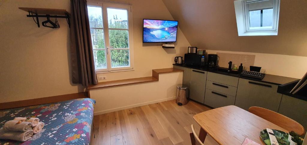 坎佩尔Appartement Studio Chanoine的厨房配有桌子,墙上配有电视。