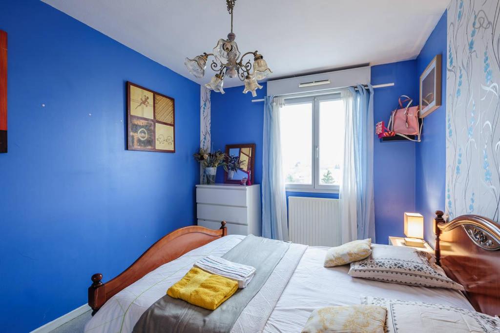 里昂COSY ROOM CROIX ROUSSE的一间卧室拥有蓝色的墙壁,配有一张带黄色枕头的床。