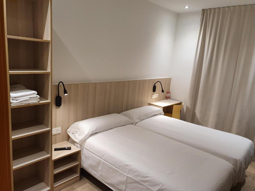 巴塞罗那奎尔伯爵旅馆的卧室配有白色的大床和架子