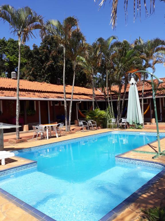 Patrimônio São SebastiãoPousada Jacare Pepira的一个带桌椅和棕榈树的游泳池