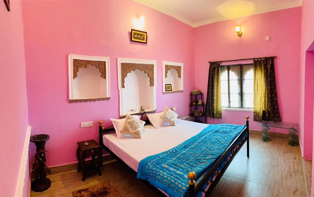 本迪The Castle View Homestay的一间卧室设有粉红色的墙壁和一张带蓝色毯子的床。