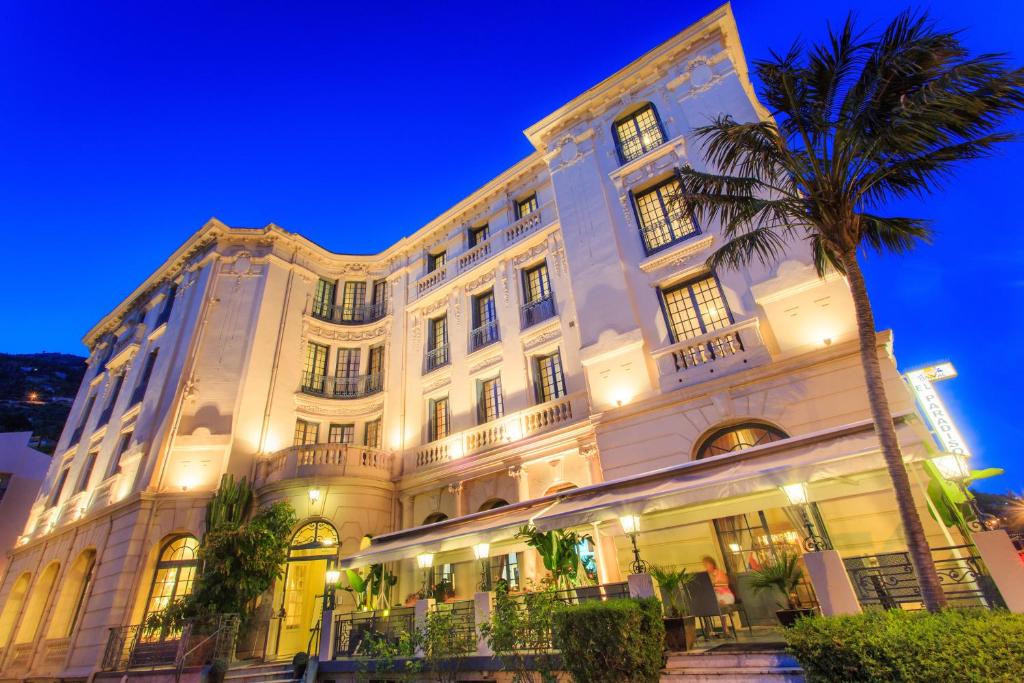 芒通帕拉迪索酒店的一座白色的大建筑,前面有一棵棕榈树