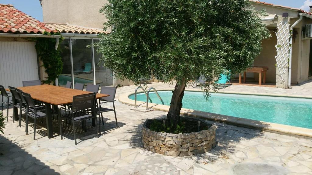 莱齐尼昂科尔比埃maison avec piscine的桌子和椅子以及泳池旁的树