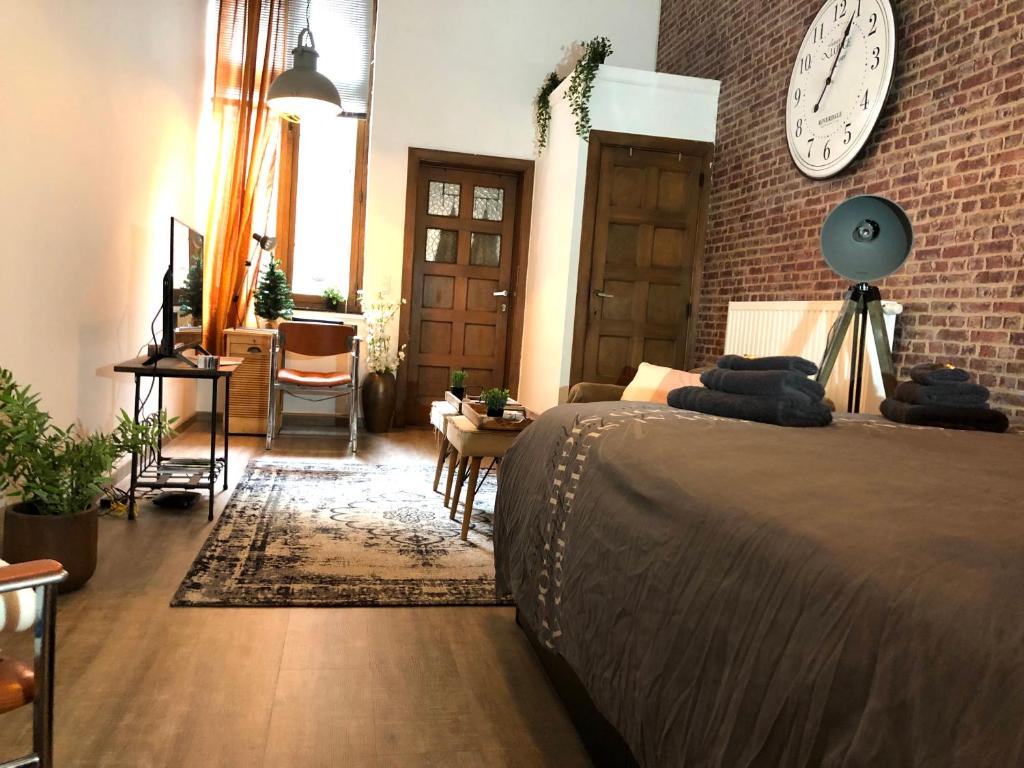 那慕尔New York Loft - Fully equipped and available long-term - Perfect location IN city center的卧室配有一张床,墙上挂着一个钟