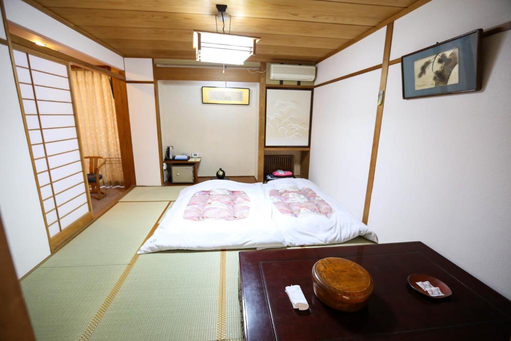 山之内町楽奇温泉旅館的小房间设有一张床和一张桌子