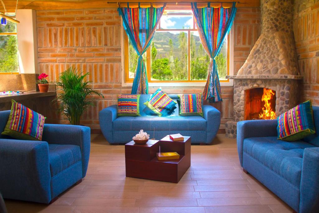科塔卡奇Watzara Wasi Cottage Familiar Camprestre Y Lofts en Cotacachi的客厅配有2张蓝色沙发和壁炉