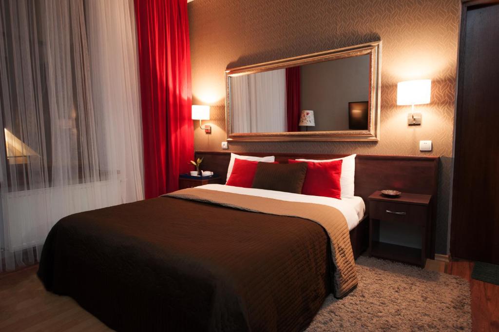 基希讷乌艺术质朴精品酒店的一间卧室配有一张带红色枕头和镜子的床