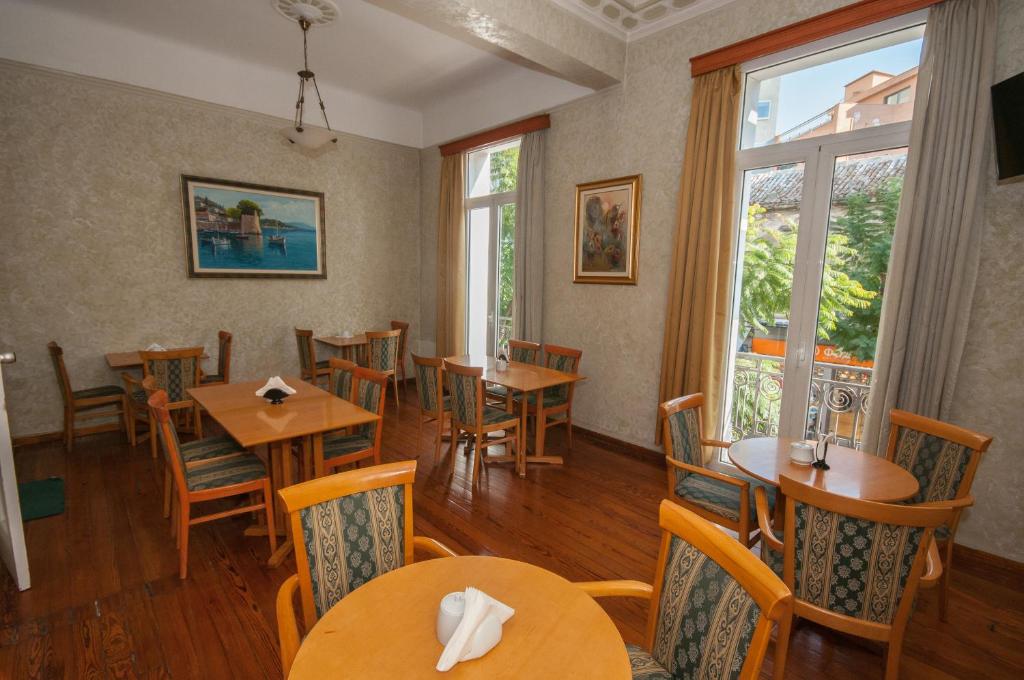 雅典塞西尔酒店的餐厅设有木桌、椅子和窗户。