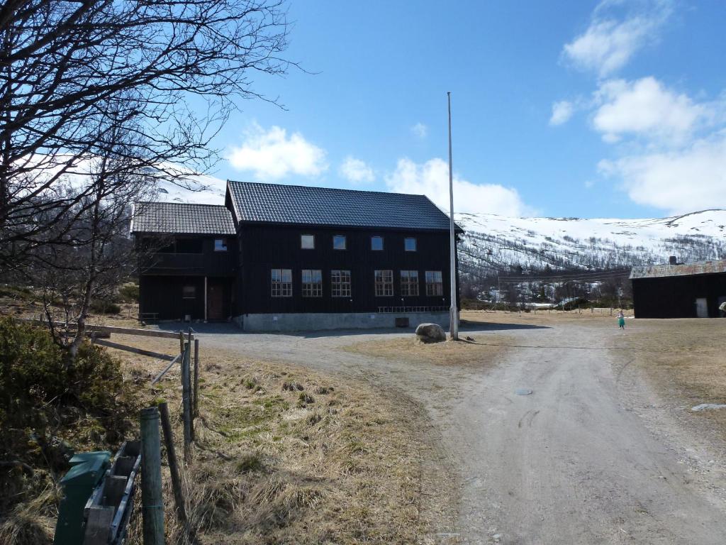 UvdalJønndalen Høyfjellseter的山地雪覆盖的泥路上的黑色建筑