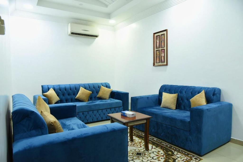 奈季兰شقق جنان المفروشة Jenaan Apartments的客厅配有2张蓝色的沙发和1张桌子