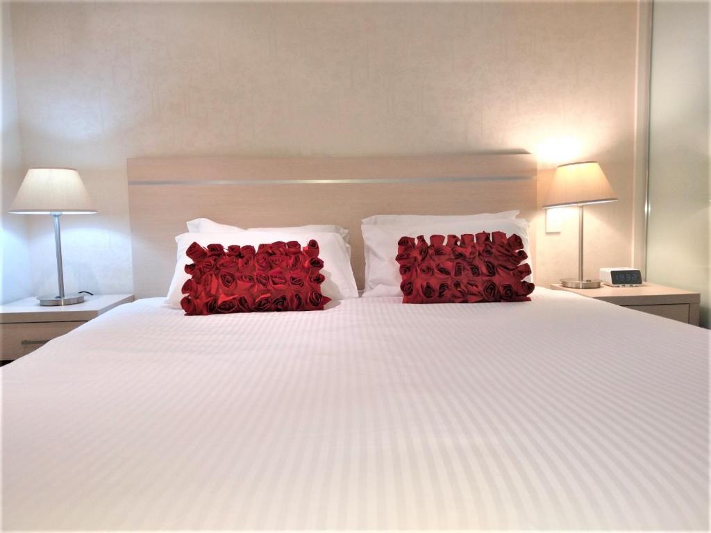阿德莱德Hi 5 star luxury Adelaide City Apartment的一张带两个红色枕头的白色床