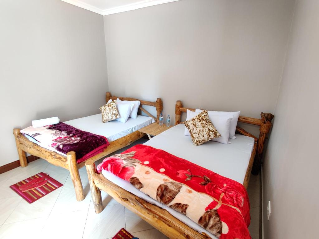 阿鲁沙Wanyama B&B的配有红色和白色毯子的客房内的两张床