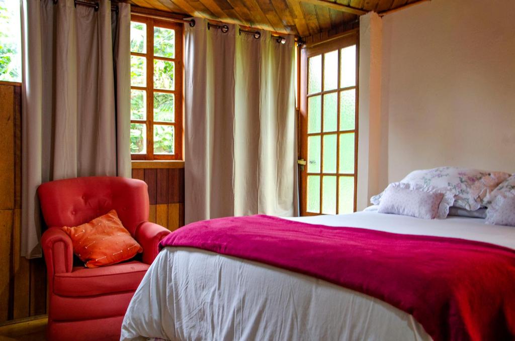 Núcleo MauáChalés Luz da Montanha的一间卧室配有一张大床和一张红色椅子