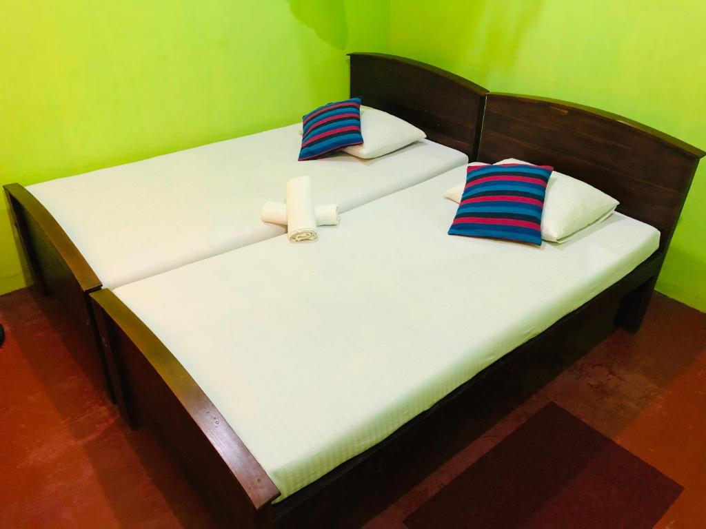 波隆纳鲁沃Kumari Guest House的绿墙客房中的两张单人床