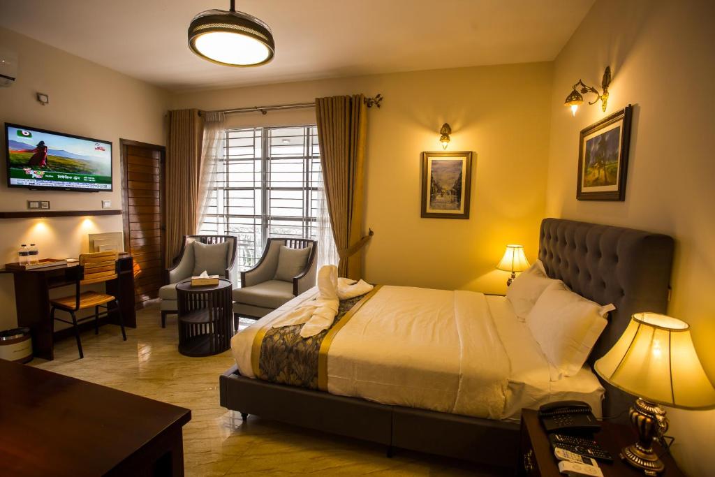达卡Shinepukur Suites的一间卧室配有一张床、一张书桌和一台电视。