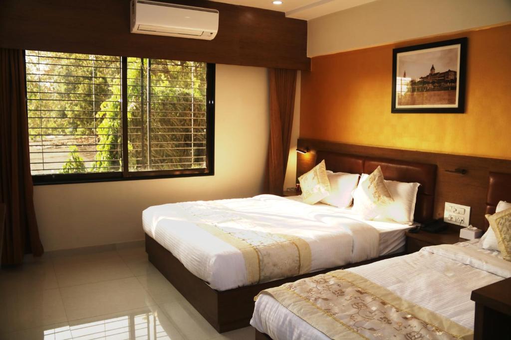 孟买Hotel Crystal Luxury Inn- Bandra的酒店客房设有两张床和窗户。