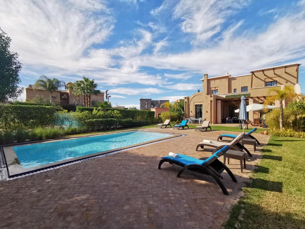 马拉喀什Marrakech Pearl的一个带躺椅的游泳池以及一座房子
