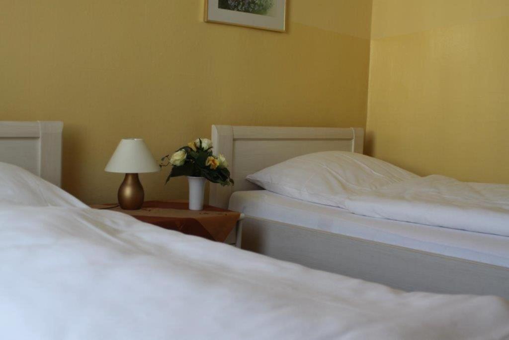 魏登威勒酒店的卧室内的两张床,配有灯和鲜花