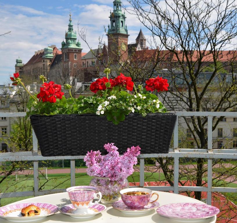 克拉科夫Castle View Boutique Apartment的围栏上带盘子、杯子和鲜花的桌子