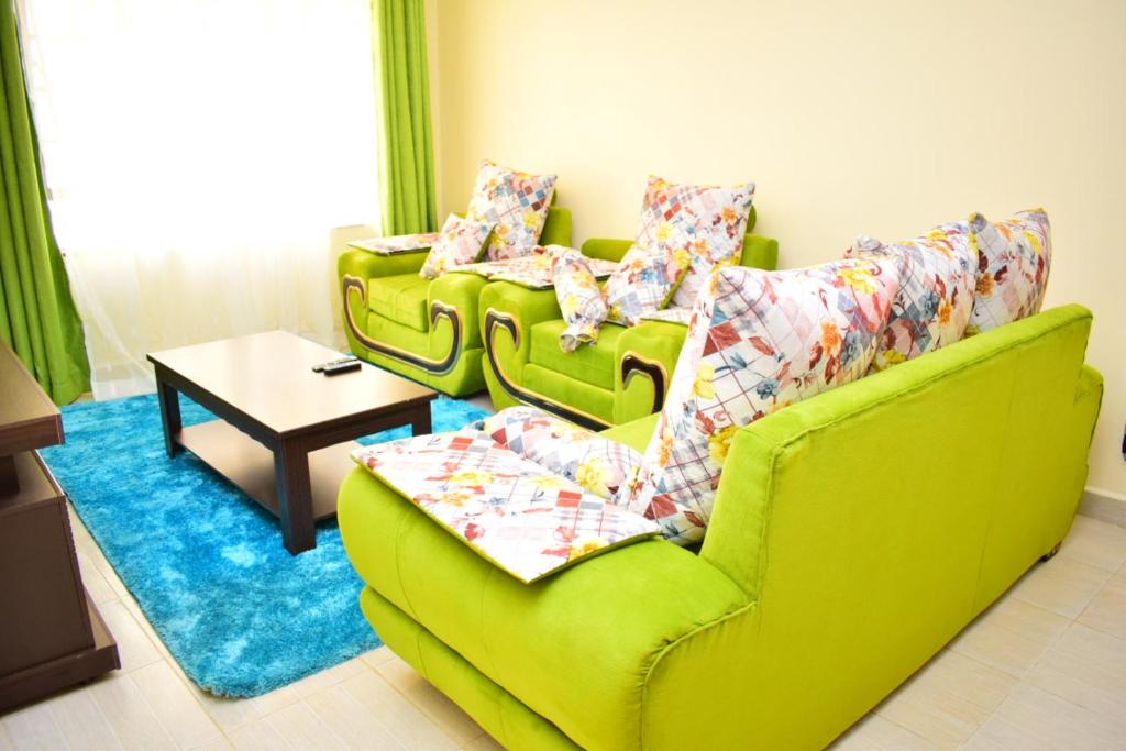 内罗毕Great house BnB near jkia的客厅配有两张绿色沙发和一张桌子