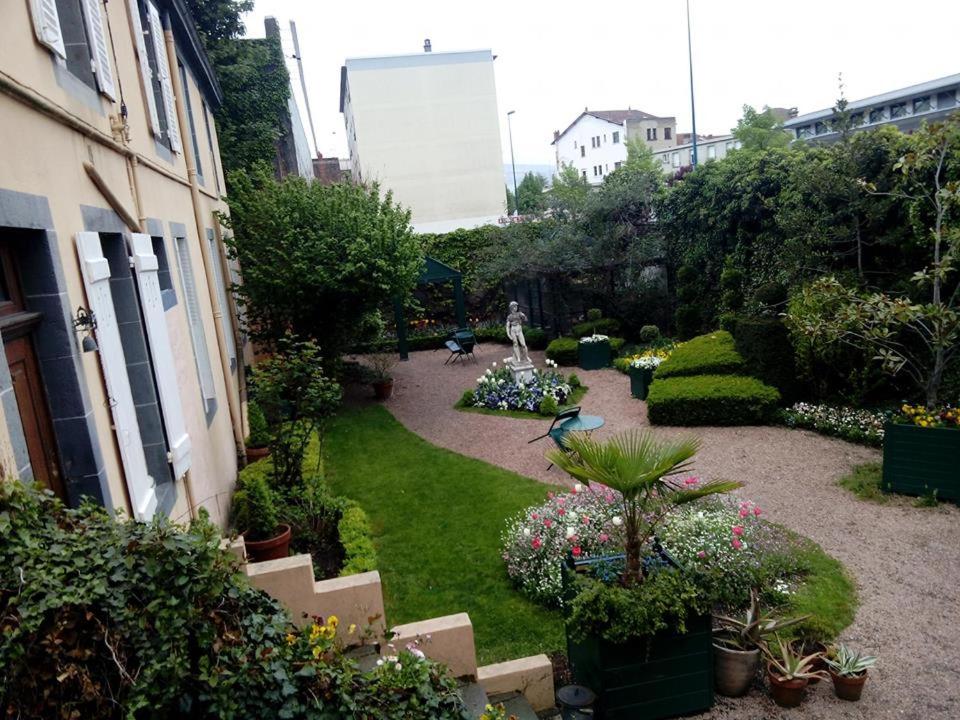 克莱蒙费朗Propriété Charbaymond的一座种植了植物和鲜花的花园,一座建筑
