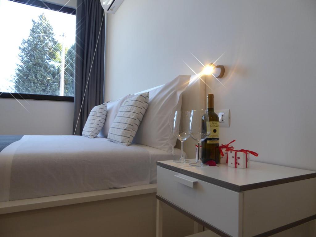 萨索马可尼Agriturismo Tenuta Bettozza的一间卧室配有一张床和一张桌子及一瓶葡萄酒