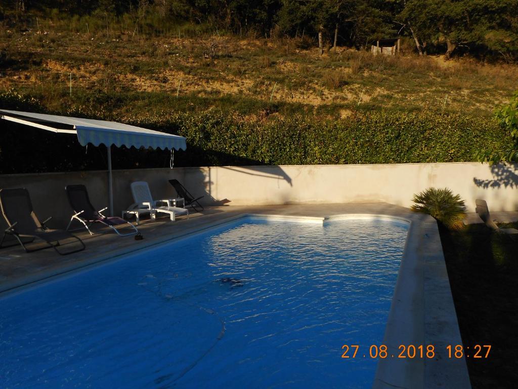 里耶LES TILLEULS的蓝色游泳池配有椅子和遮阳伞