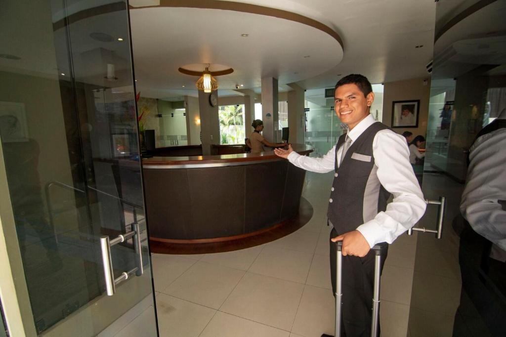 伊基托斯El Dorado Classic Hotel的站在酒吧旁的男朋友,穿着背心和领带