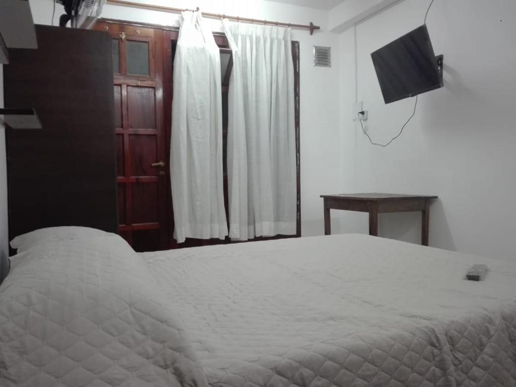 圣萨尔瓦多德朱Apart Jujuy monoambiente的卧室配有白色的床和电视。