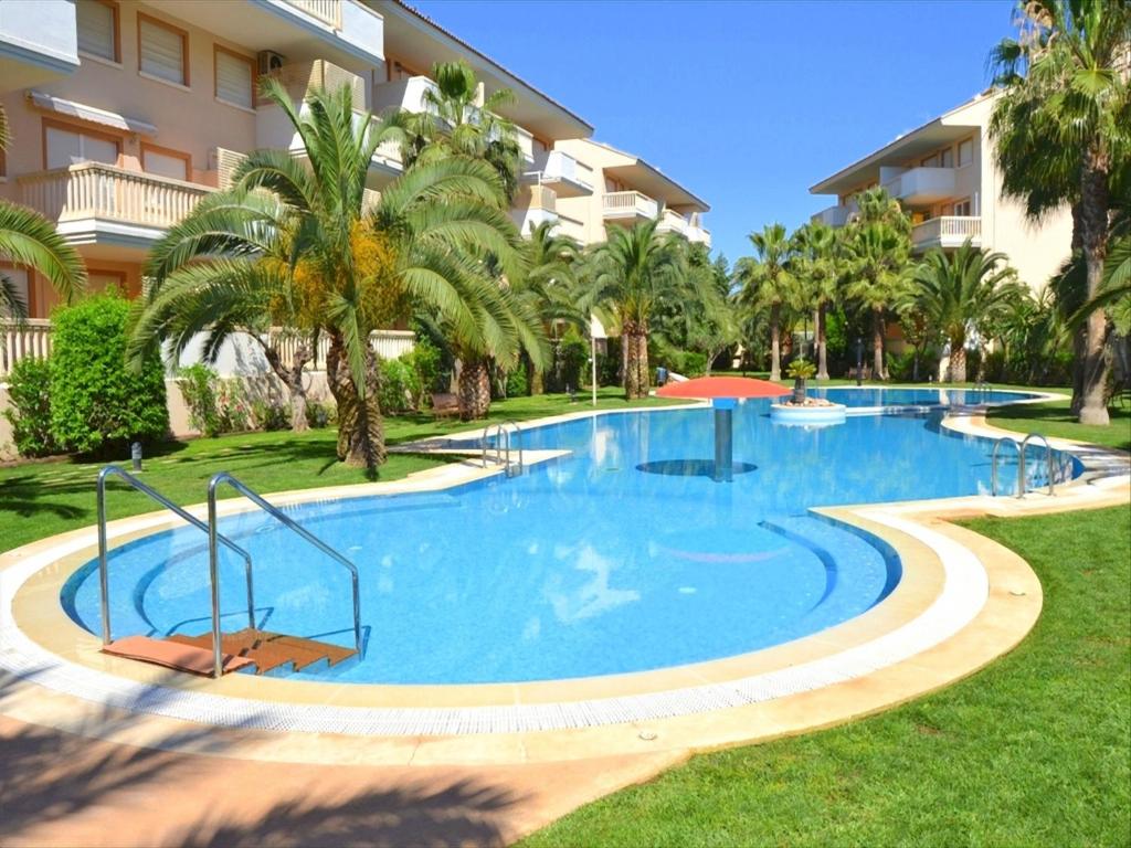 哈维亚Apartamento Nou Fontana的一座大型游泳池,在一座建筑前种有棕榈树