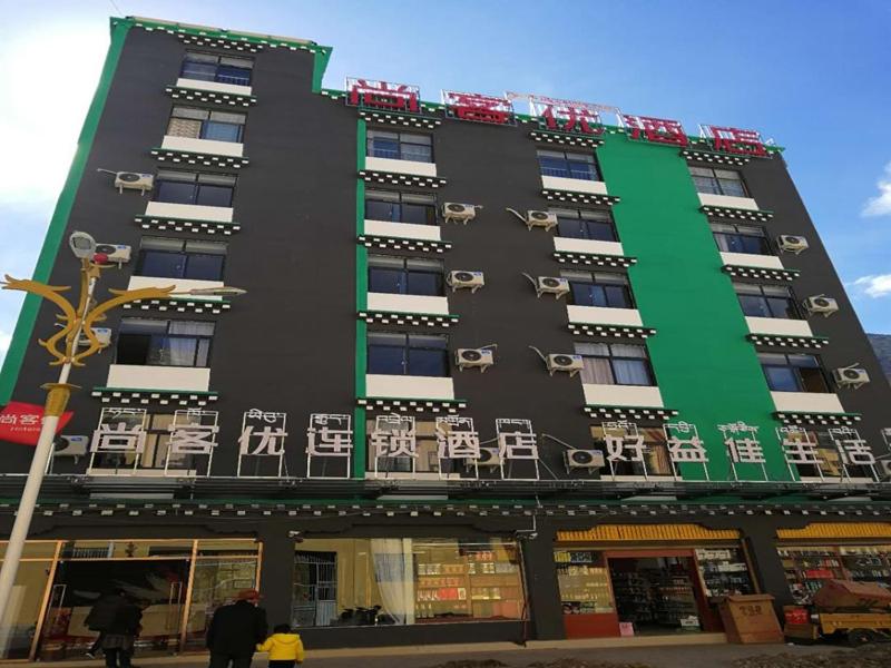 Baima尚客优酒店西藏昌都八宿县县政府店的一座黑色和绿色的建筑,里面摆放着椅子