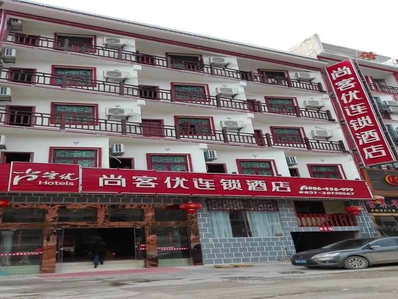 安顺尚客优酒店贵州安顺黄果树风景名胜区店的一座白色的大建筑,上面有红色的标志