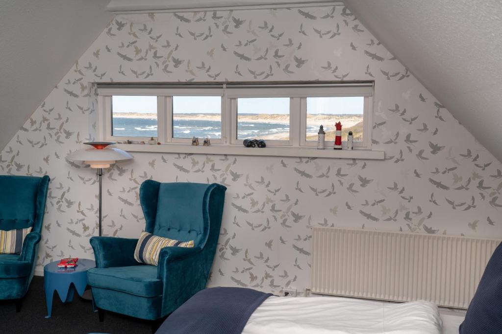 克利特默勒Klitmøller Hotel的一间卧室配有一张床、两把椅子和一个窗户