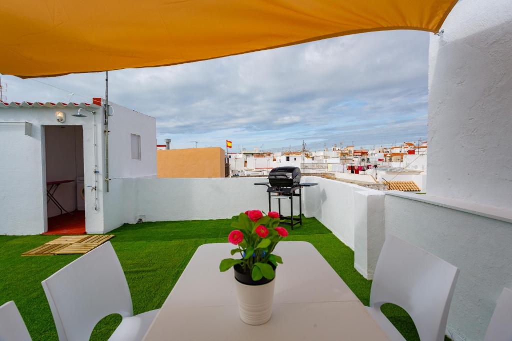 罗塔La Terraza del POETA by Cadiz4Rentals的屋顶上带桌子和鲜花的阳台