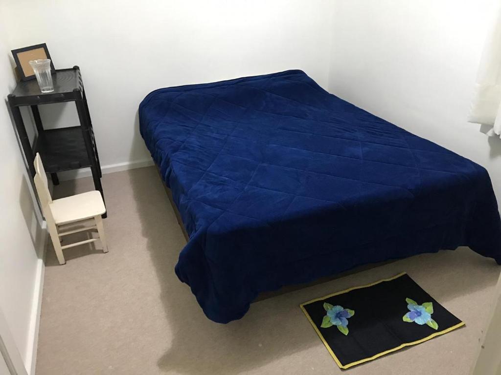 库里提巴Quarto aconchegante nas Mercês的一间卧室配有蓝色的床和床头柜