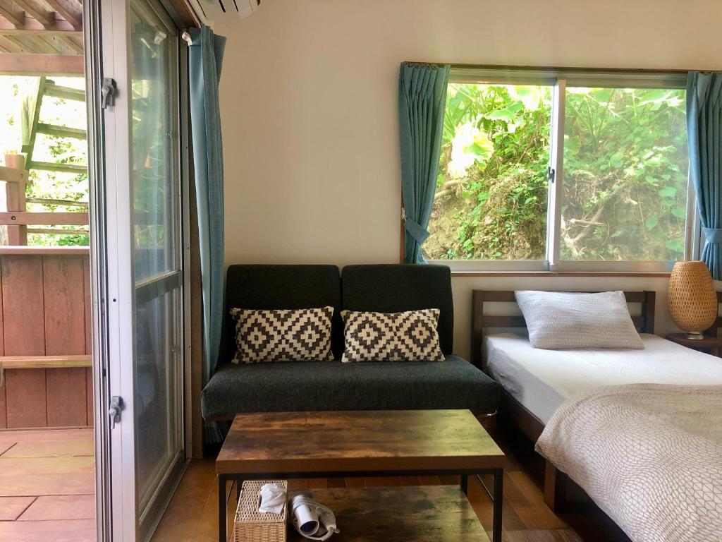 读谷村人生旅程旅馆的一间配有沙发、一张床和窗户的客房