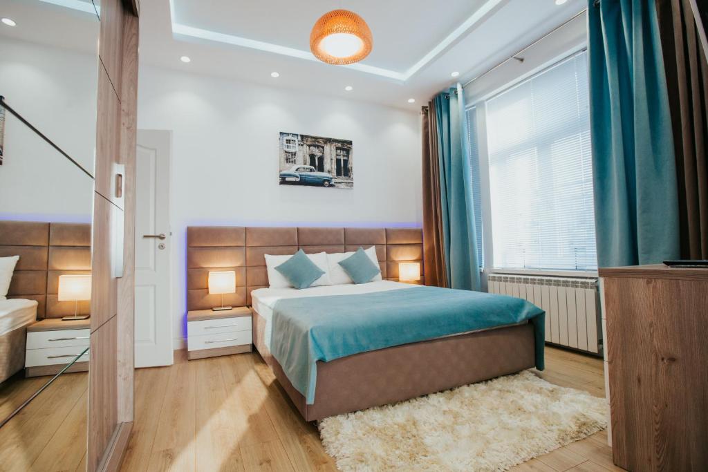 布加勒斯特Color Apartments Corneliu Coposu 1A street的一间卧室配有一张带蓝色床单的床和一扇窗户。