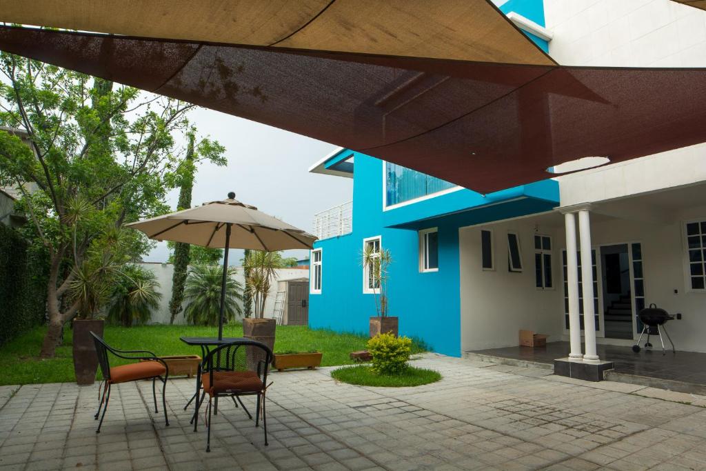 San Lorenzo CacaotepecCasa Gloria的蓝色的建筑,配有桌椅和雨伞